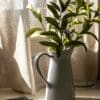 a plant in a white vase next to a book